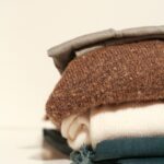 Neatly folded stack of cozy sweaters showcasing textures and layers.