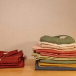 Neatly folded colorful clothes on a wooden table, showcasing texture and style.